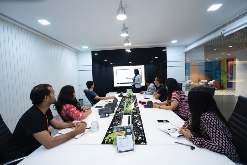 people sitting at the table looking to another person standing in front of them