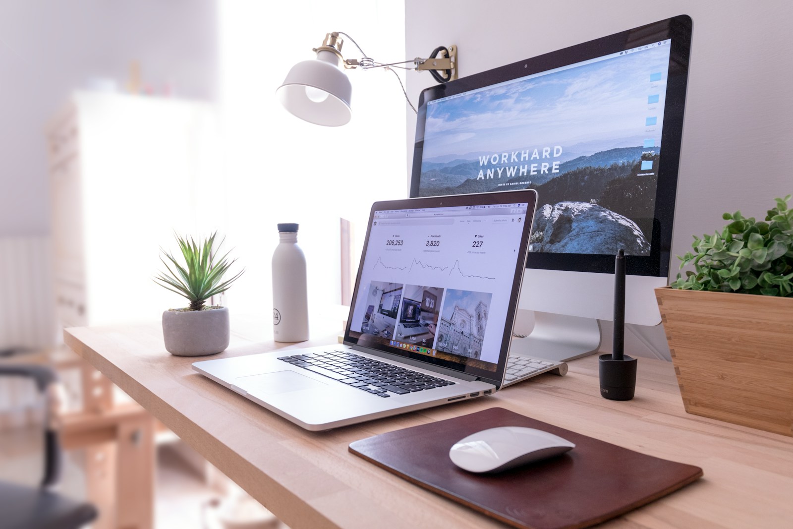 MacBook Pro on table beside white iMac and Magic Mouse, desk chair