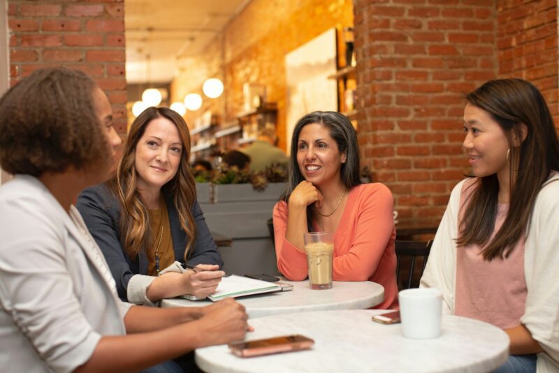 woman in black jacket sitting beside woman in white blazer, team building strategies